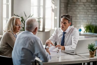 Financial advisor and senior couple talking while going through paperwork on a meeting. Financial advisor and senior couple talking while going through paperwork on a meeting.
